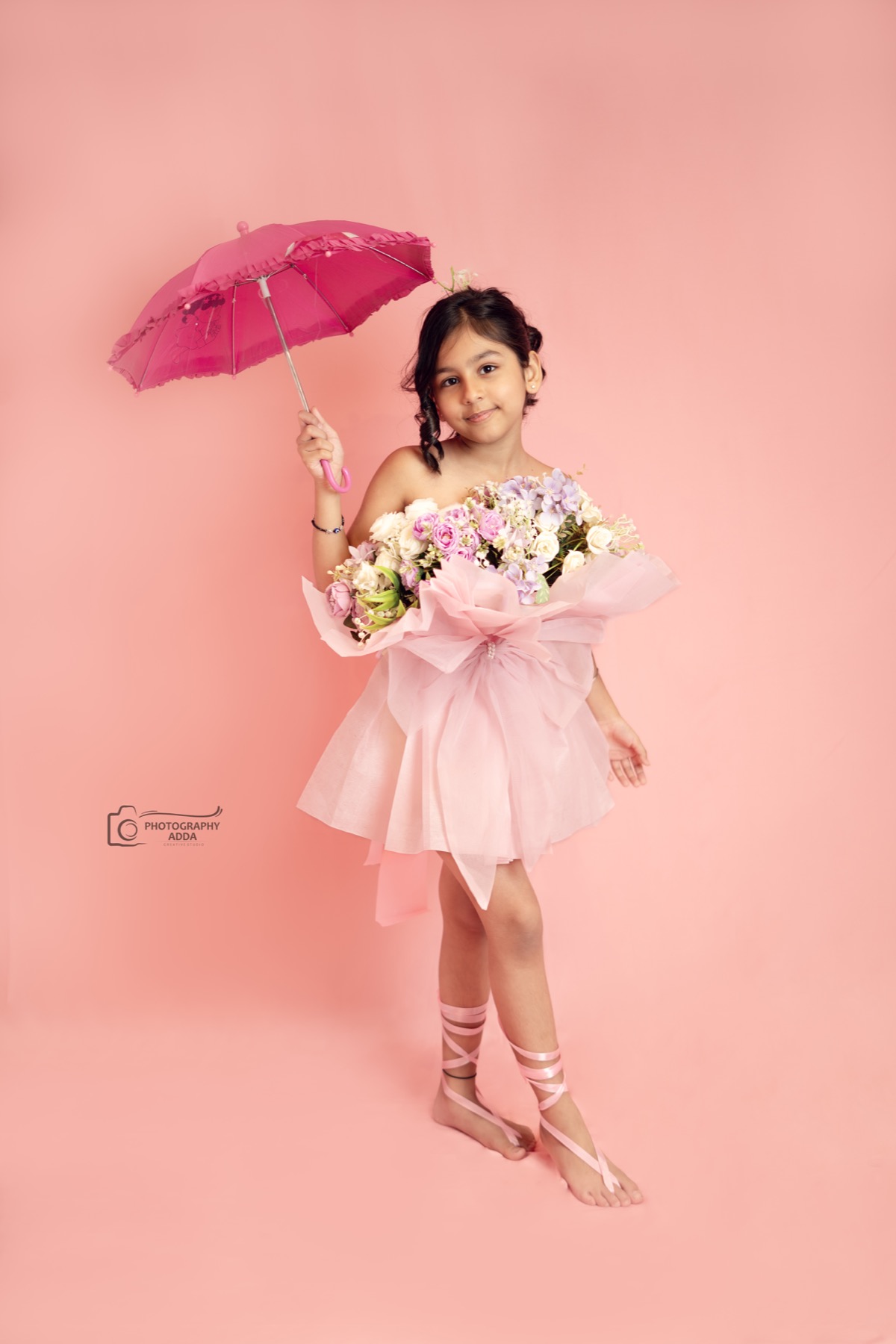 Kids photoshoot with pink umbrella and floral dress by Photography Adda