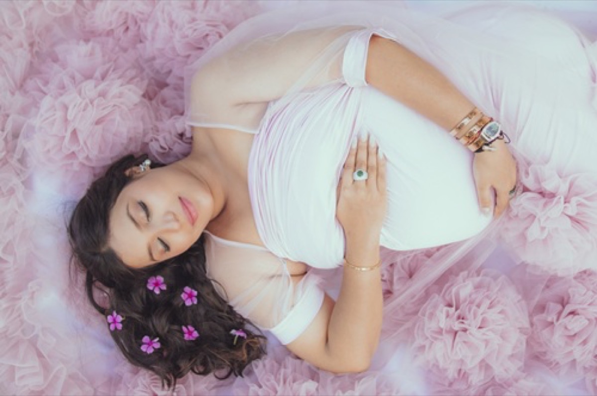 Luxury maternity baby bump photoshoot in pink floral studio setup